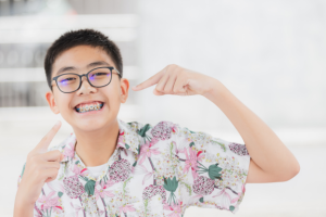 Smiling tween shows off his top and bottom teeth braces for his treatment plan