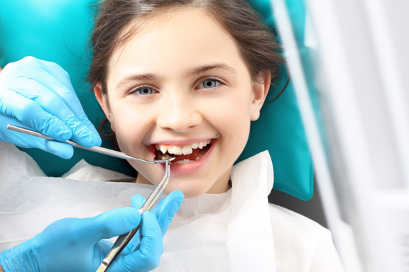 A smiling new female patient in a dental chair getting an oral exam 