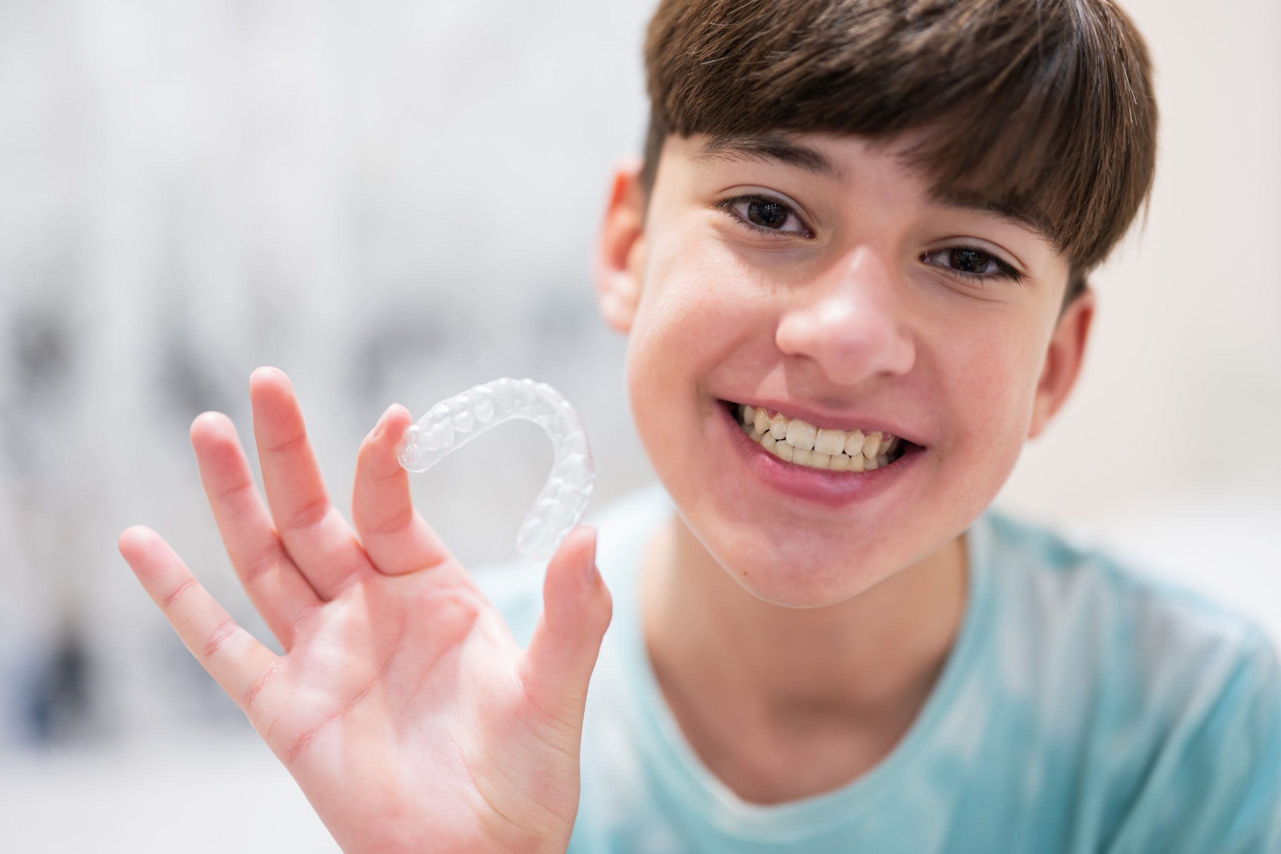 Kid needing to know how to fix a gummy smile and is using Invisalign