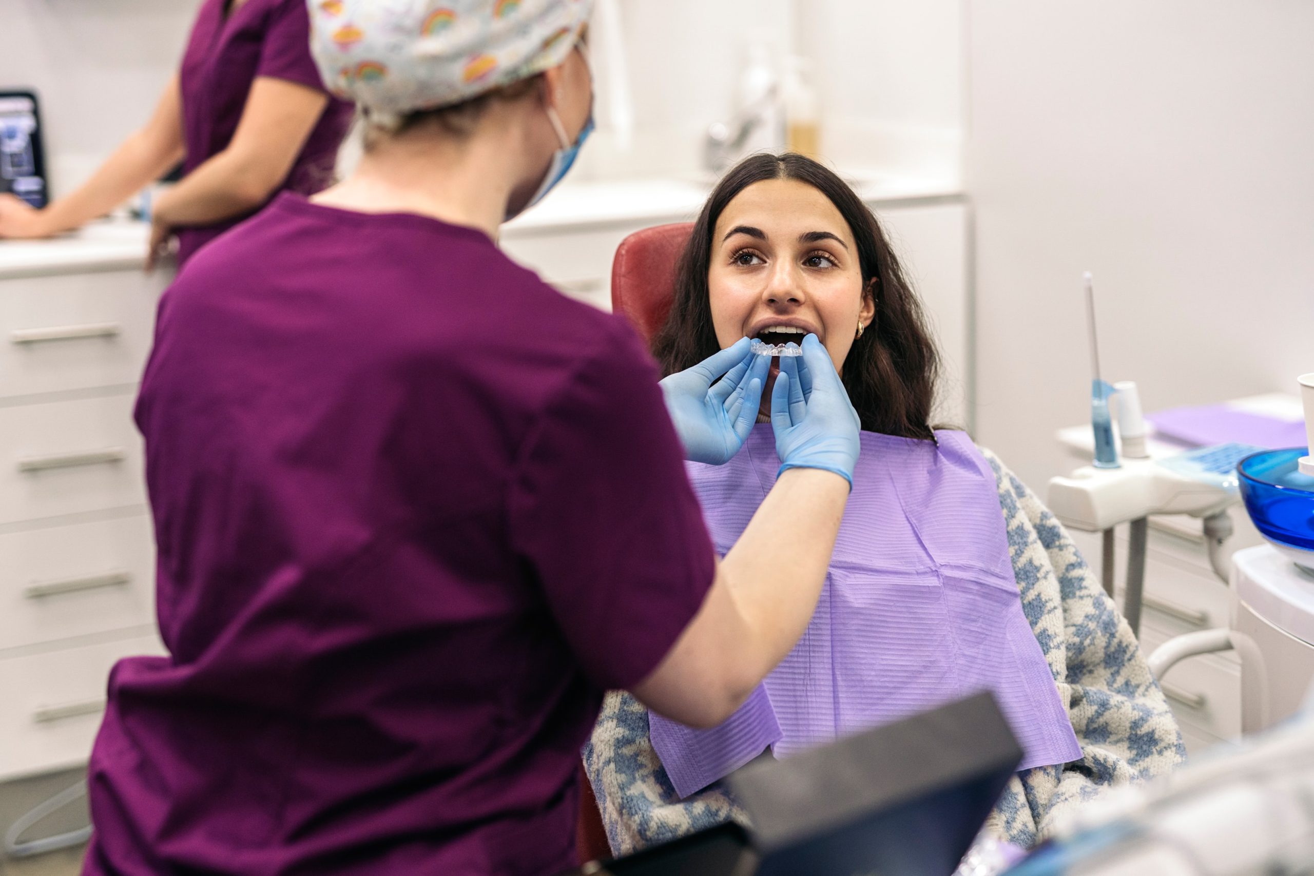 A female orthodontist helping a patient with their new Invisalign in Calgary