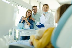 Happy family at visit in the orthodontist office talking about traditional braces