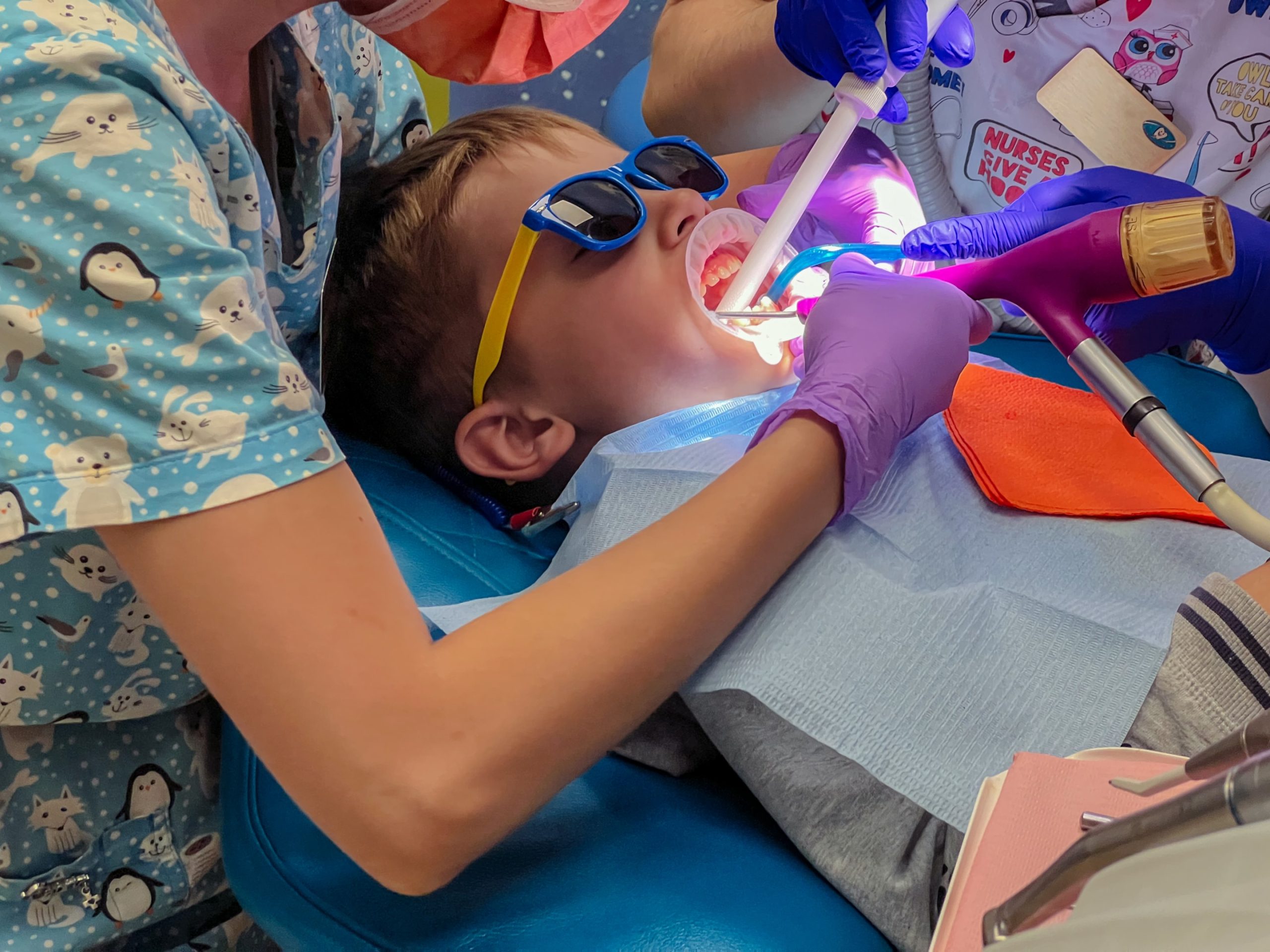 A pediatric dentists cleaning a young boys teeth.