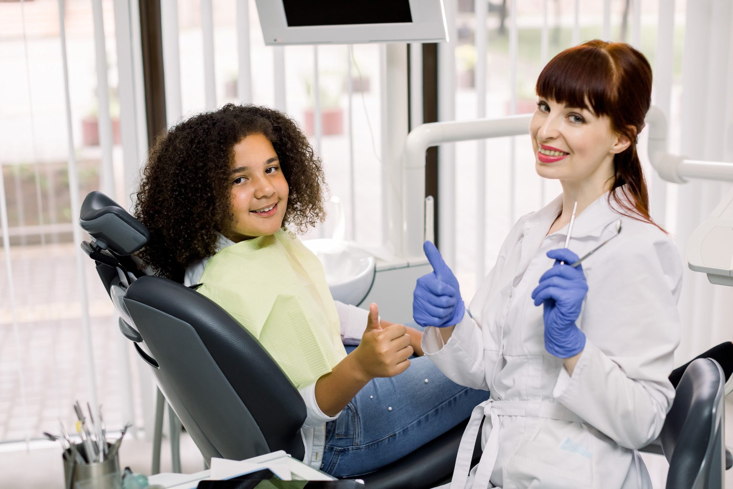 A young patient in a dental chair getting ready for her orthodontic evaluation by her kid orthodontic dentist 