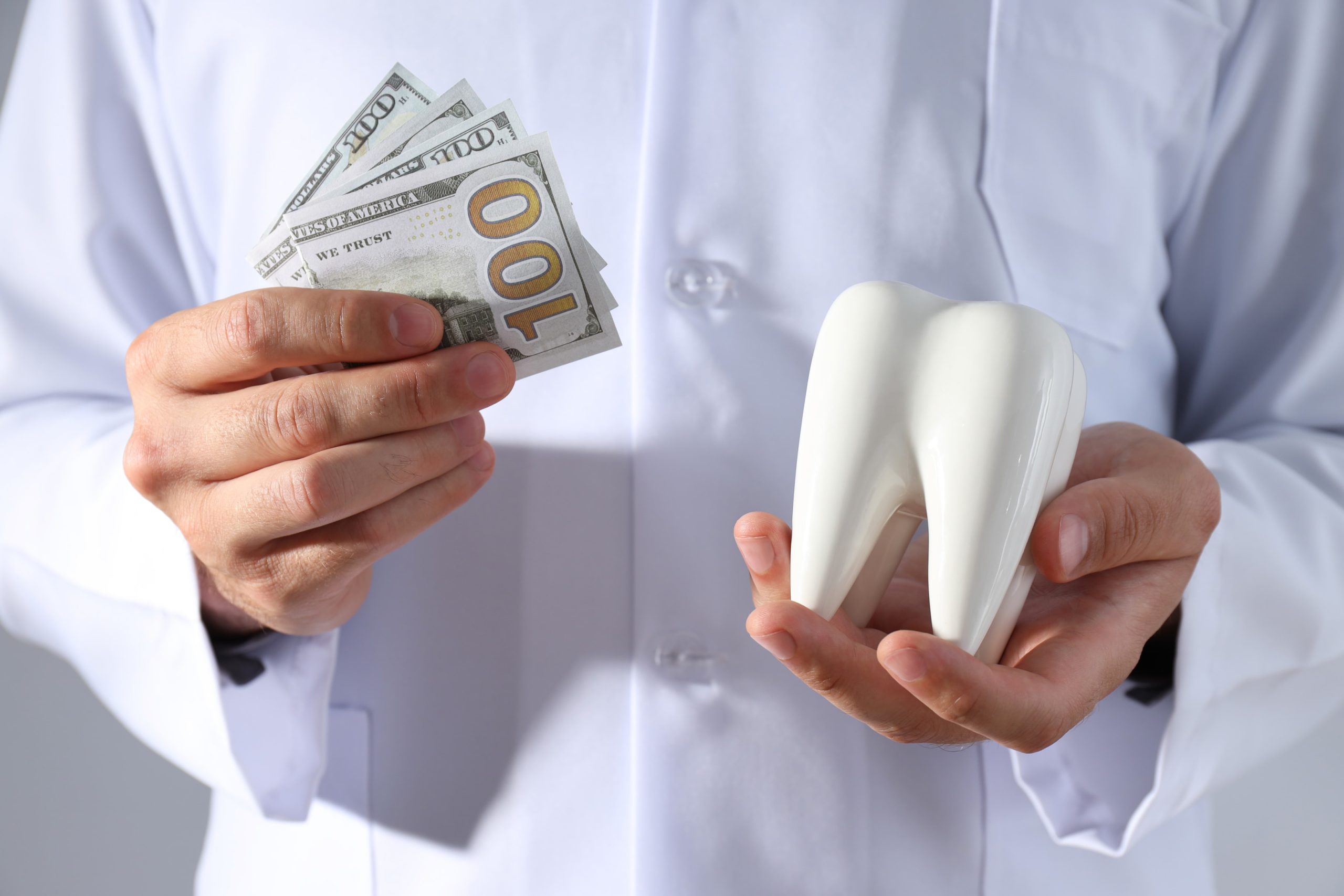 Dollars and tooth in hands of orthodontist showing insurance cover orthodontic care