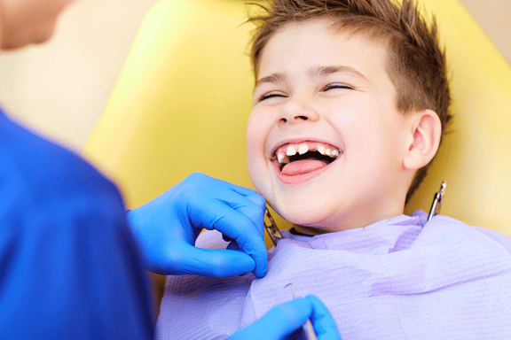 little boy laughing in dental chair 