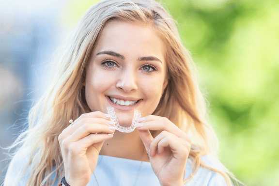 teen girl inserting invisalign tray into her mouth