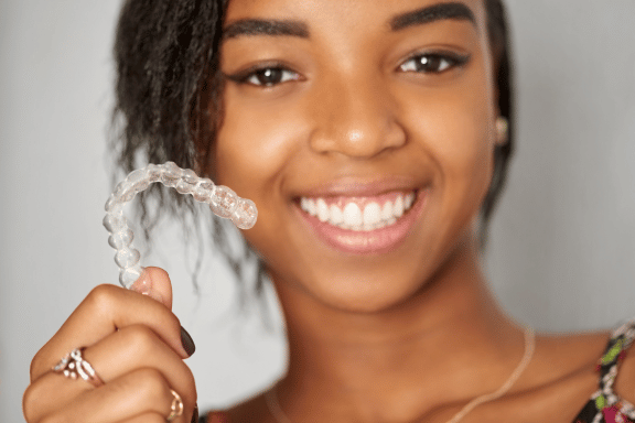 teen girl holding up her clear aligners 