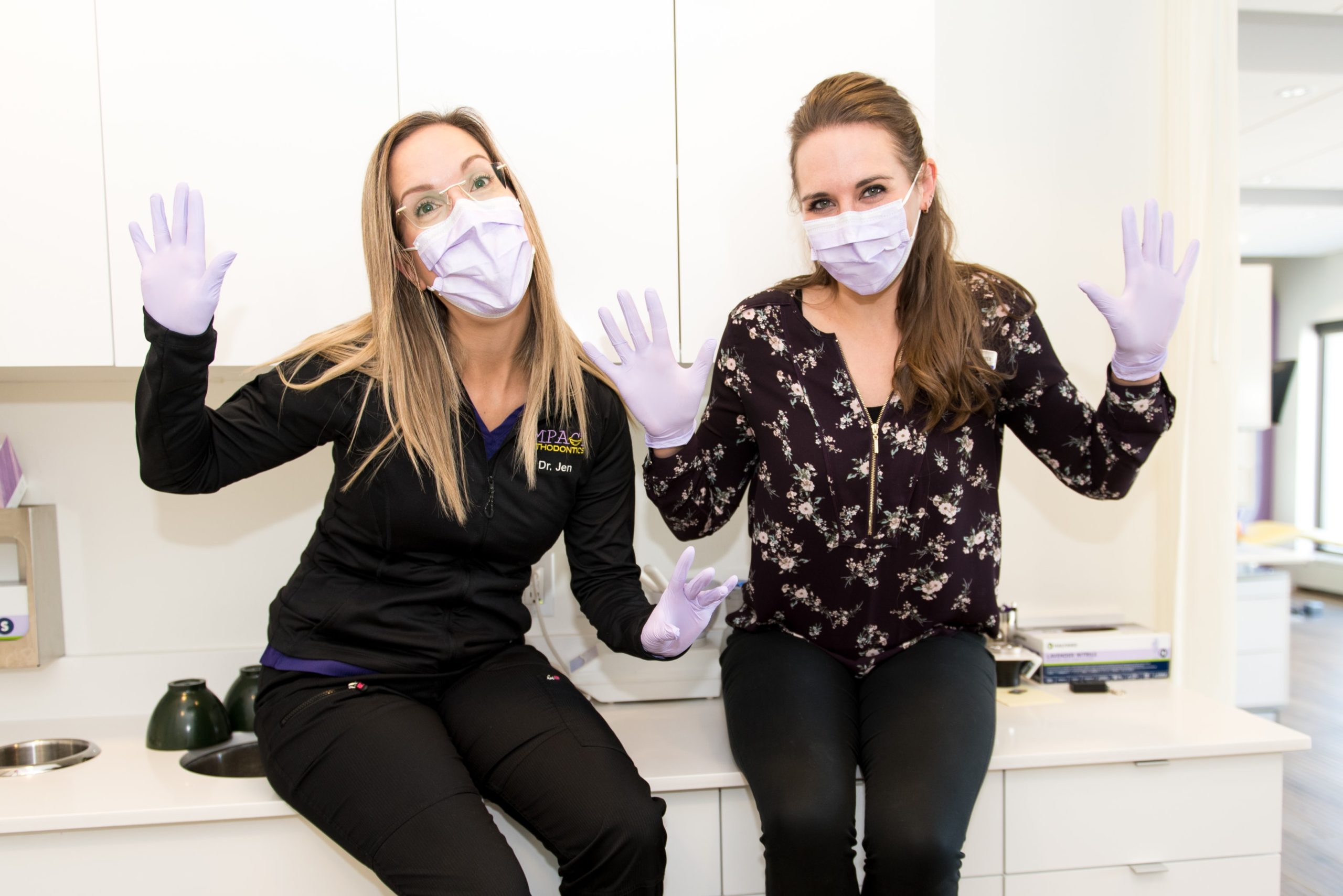 Dr. Jen and Dr. Dena in gloves and masks inside Impact Orthodontics 