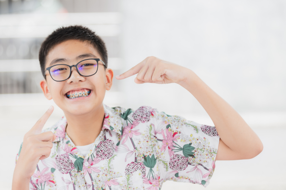 teen boy pointing to his new metal braces 