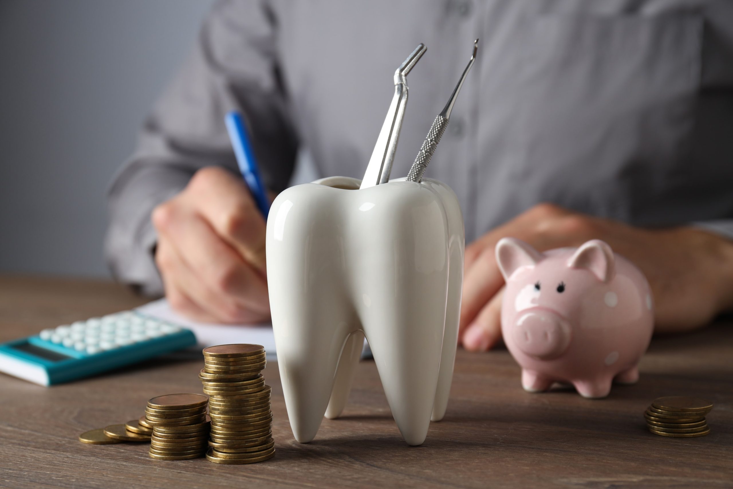 a calculator, piggy bank and tooth vase holding dental tools