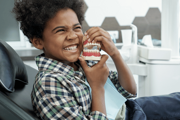 young boy holding a dental model