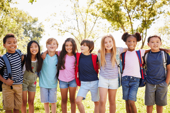 group of children smiling standing with their arms around each other