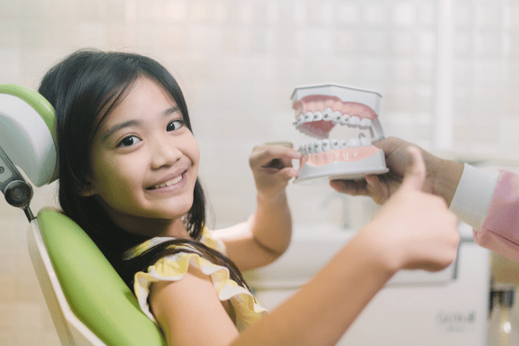 girl in dental chair with dental model discussing treatment options