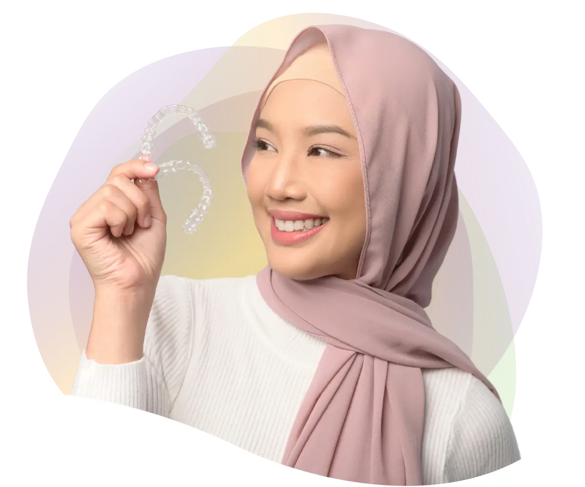 smiling muslim woman who is holding two clear aligners