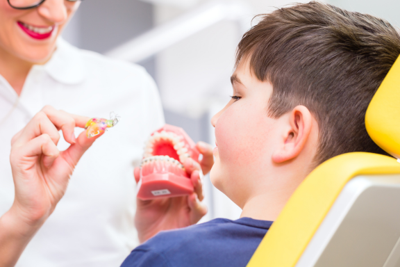 A boy in a dental chair being shown braces and a retainer to correct jaw alignment for children near me 