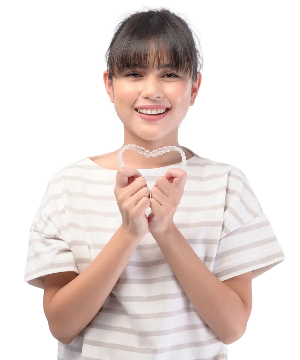 teenage girl holding 2 clear aligners in the shape of a heart