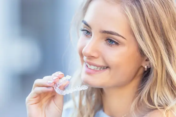 teen installs clear aligner on top teeth for overbite correction