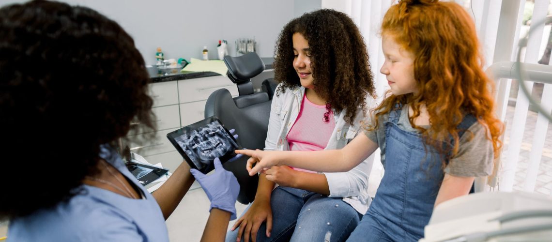 two children looking at a dental x-ray with their pediatric dentist