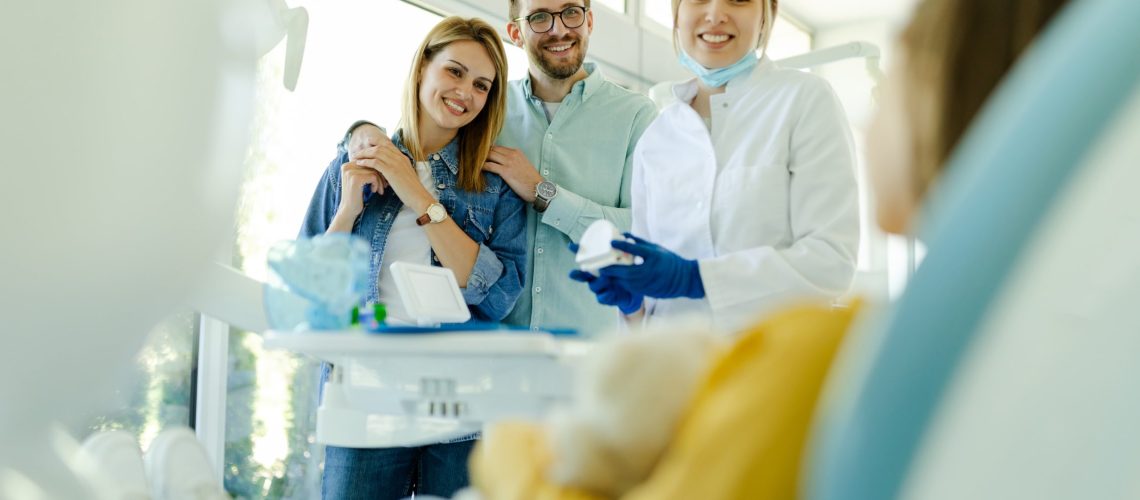 Happy family at visit in the orthodontist office talking about traditional braces